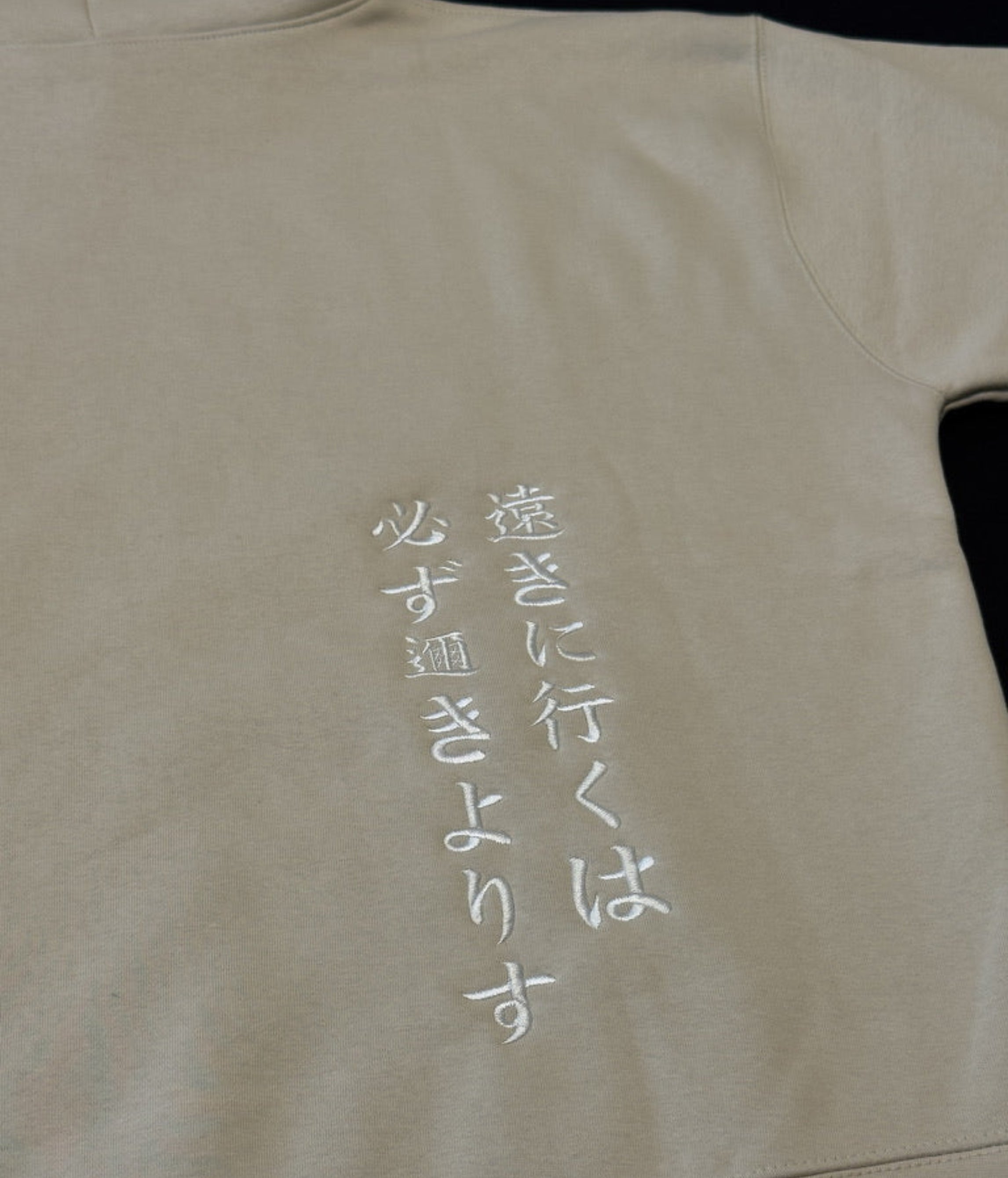 Bone hoodie with 'tooki ni iku wa kanarazu chikakiyorisu' on the back