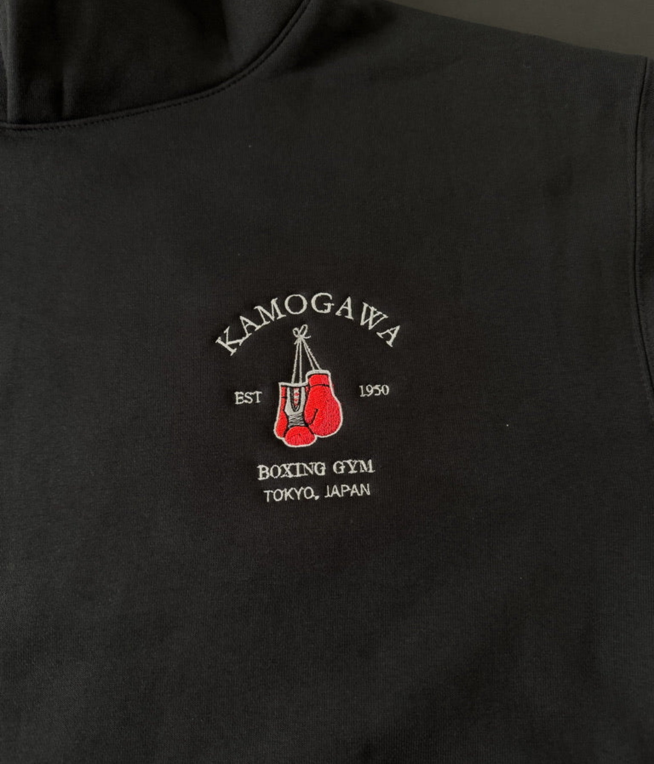 Black hoodie with a boxing gloves and ‘Kamogawa Boxing Gym’ on the chest