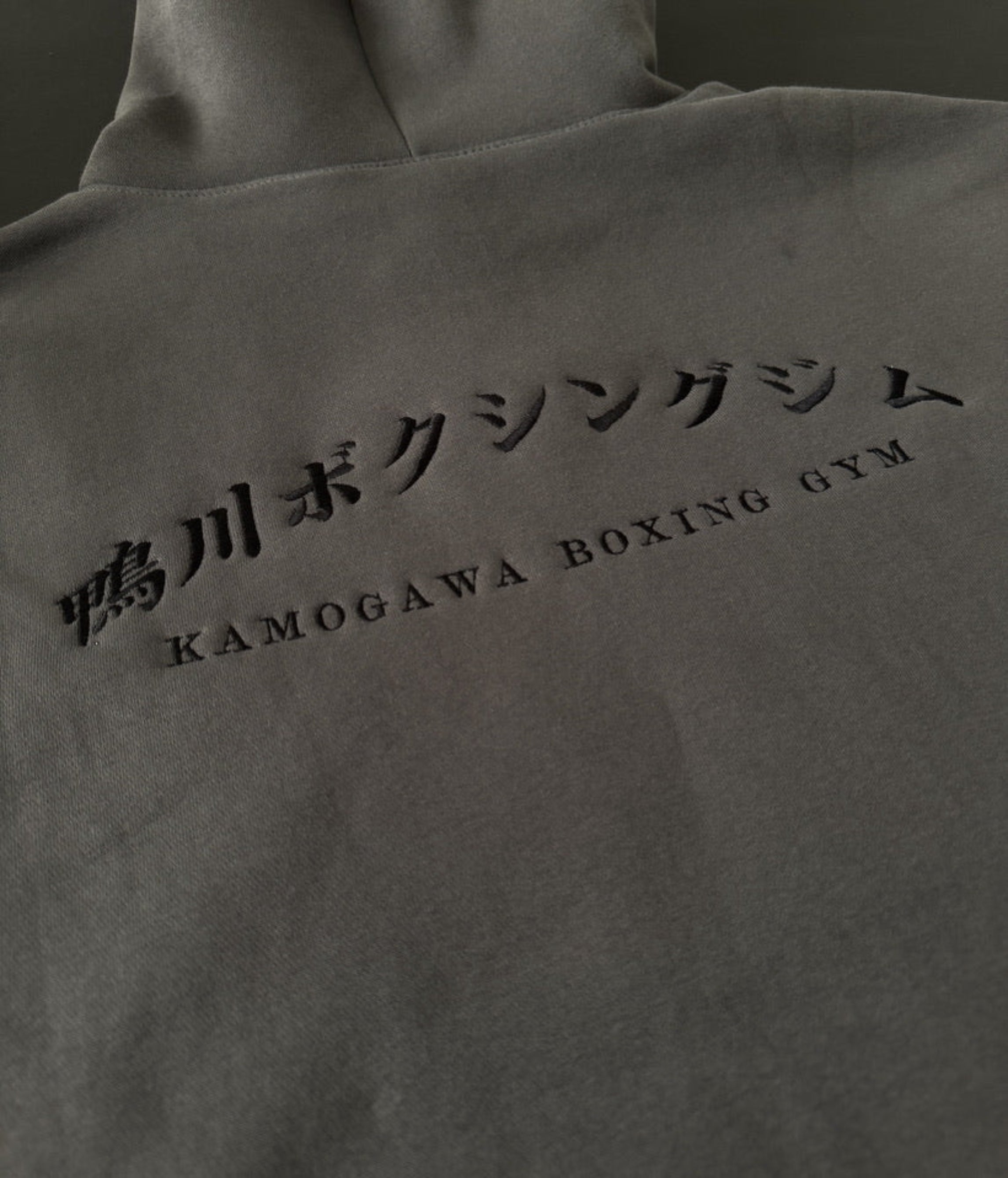 Shadow hoodie with 'Kamogawa Bokushingu Jimu' on the back