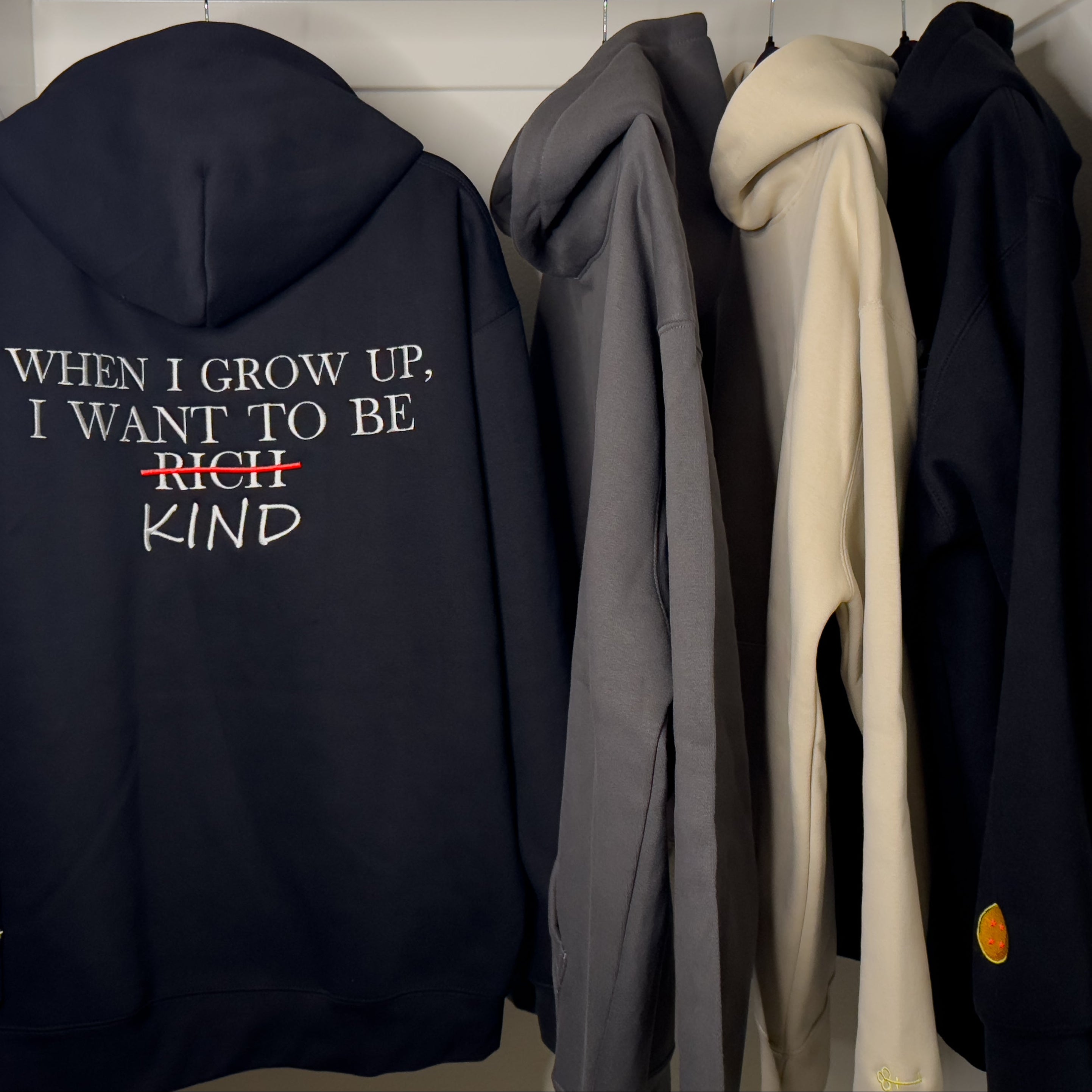 Black hoodie with text on a rack of other hoodies