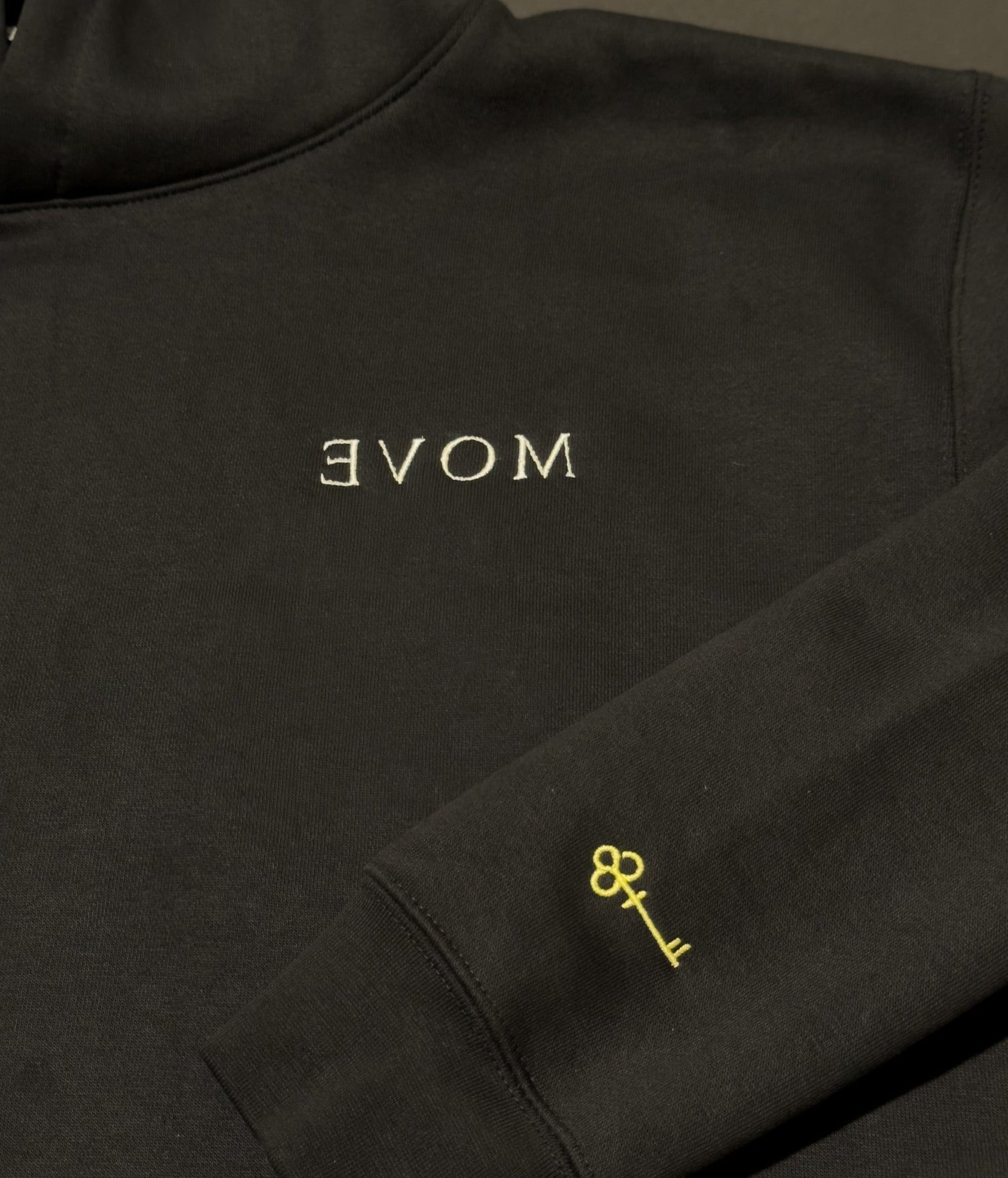 Black sweatshirt with 'MOVE' and key emblem on a dark background